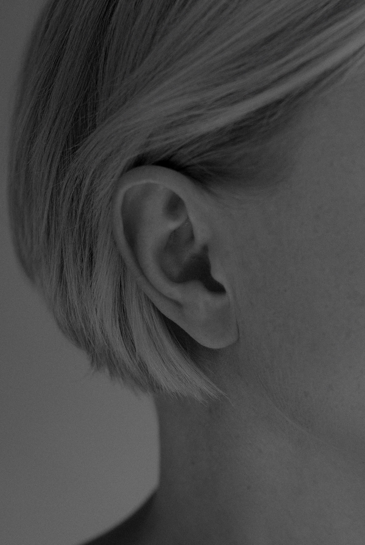 Schwarz-weiß Foto des rechten Ohrs einer schönen, jungen Frau mit Kurzhaarfrisur - auf der Seite "Leistungsspektrum" von www.hanseatic-facelift.de unter der Rubrik "Ohrkorrekturen" (Otoplastik) - "Den Ohren ergeht es wie der Nase. Sie erregen nur dann Aufmerksamkeit, wenn sie von der Norm abweichen – also abstehen, sehr groß sind, usw. Die Otoplastik korrigiert die abstehenden Ohren oder Tassenohren und jede Art von Missbildung oder Unfallfolgen. Eine Otoplastik ist eine Operation der Ohren. Sie korrigiert deren Ästhetik – etwa im Falle abstehender Ohren oder Tassenohren sowie jede Art von Missbildung oder Unfallfolgen. Durch den Eingriff lassen sich mentale Barrieren durch ästhetische Korrekturen abbauen. Die Otoplastik ist bereits bei kleineren Kindern durchführbar sowie bei Männern und Frauen aller Altersgruppen möglich".