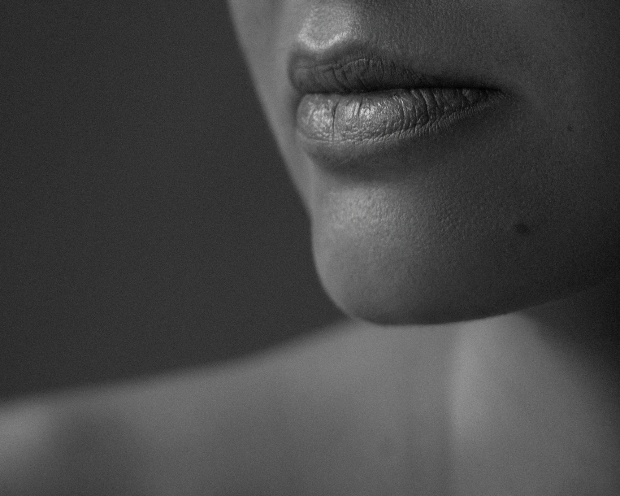 Schwarz-Weiß-Nahaufnahme von Lippen, Kinn und Schulter einer Frau