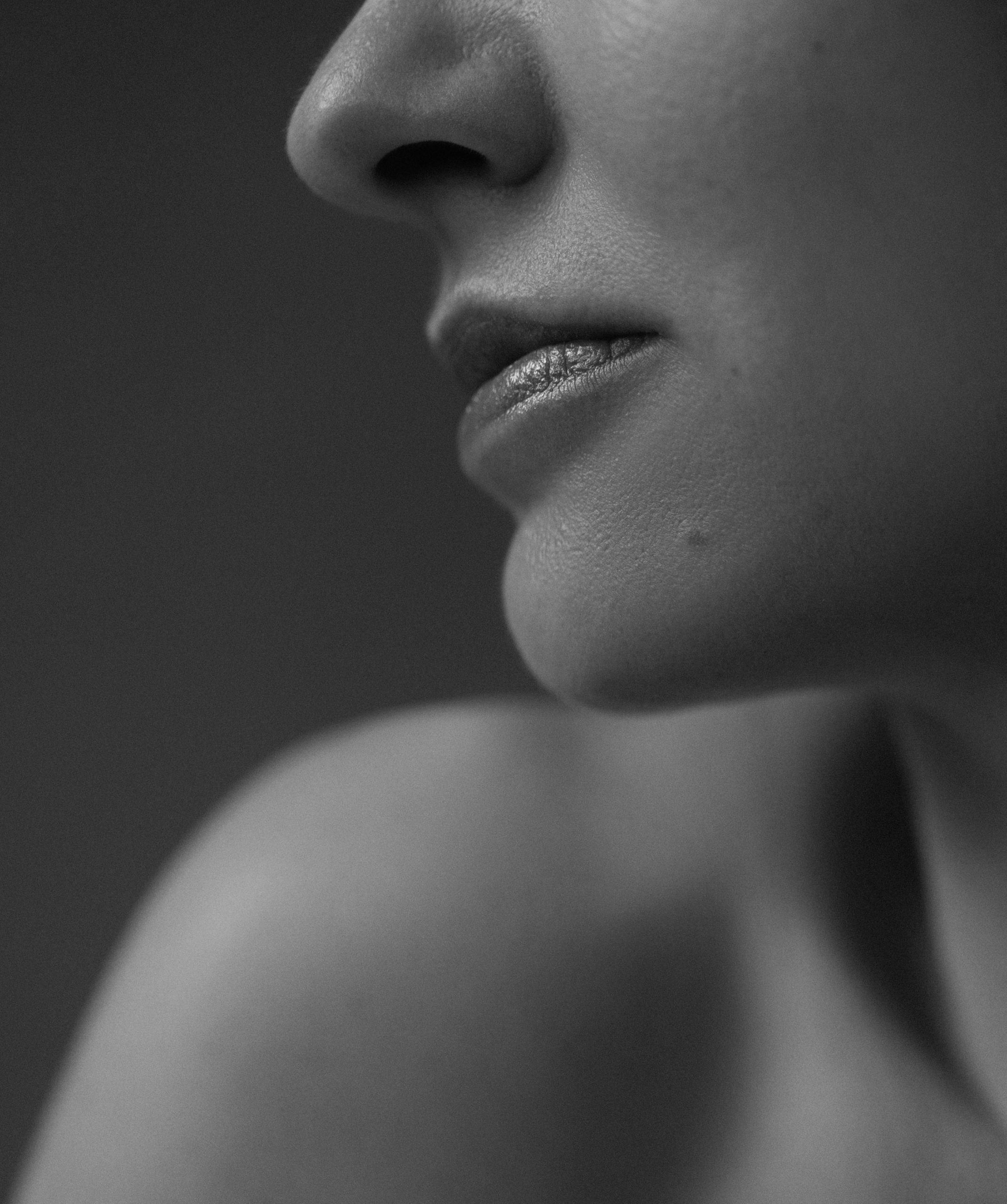 Schwarz-Weiß-Aufnahme von Lippen, Kinn und Schulter einer Frau