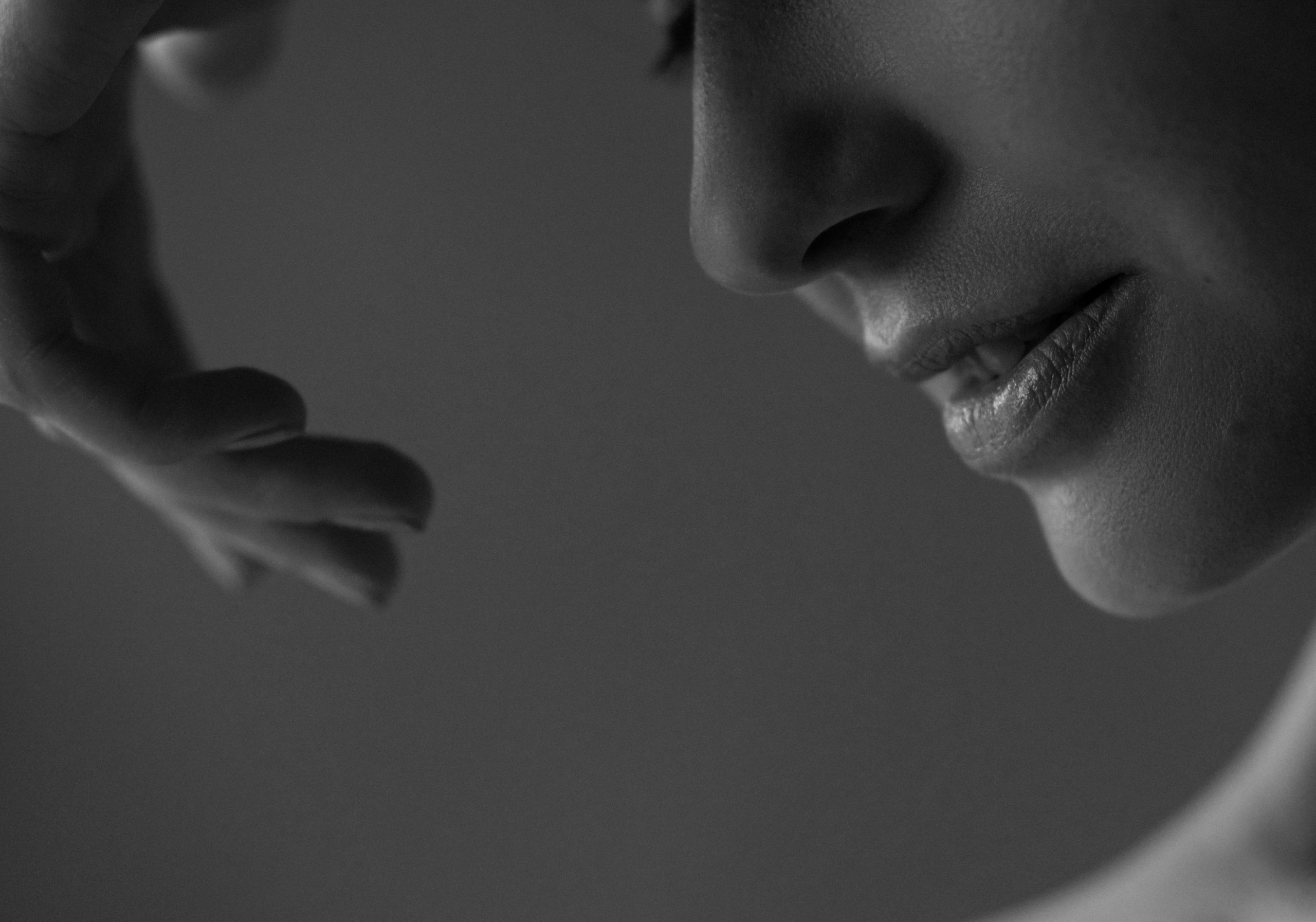 Schwarz-Weiß-Aufnahme eines weiblichen Gesichts mit Hand im Vordergrund